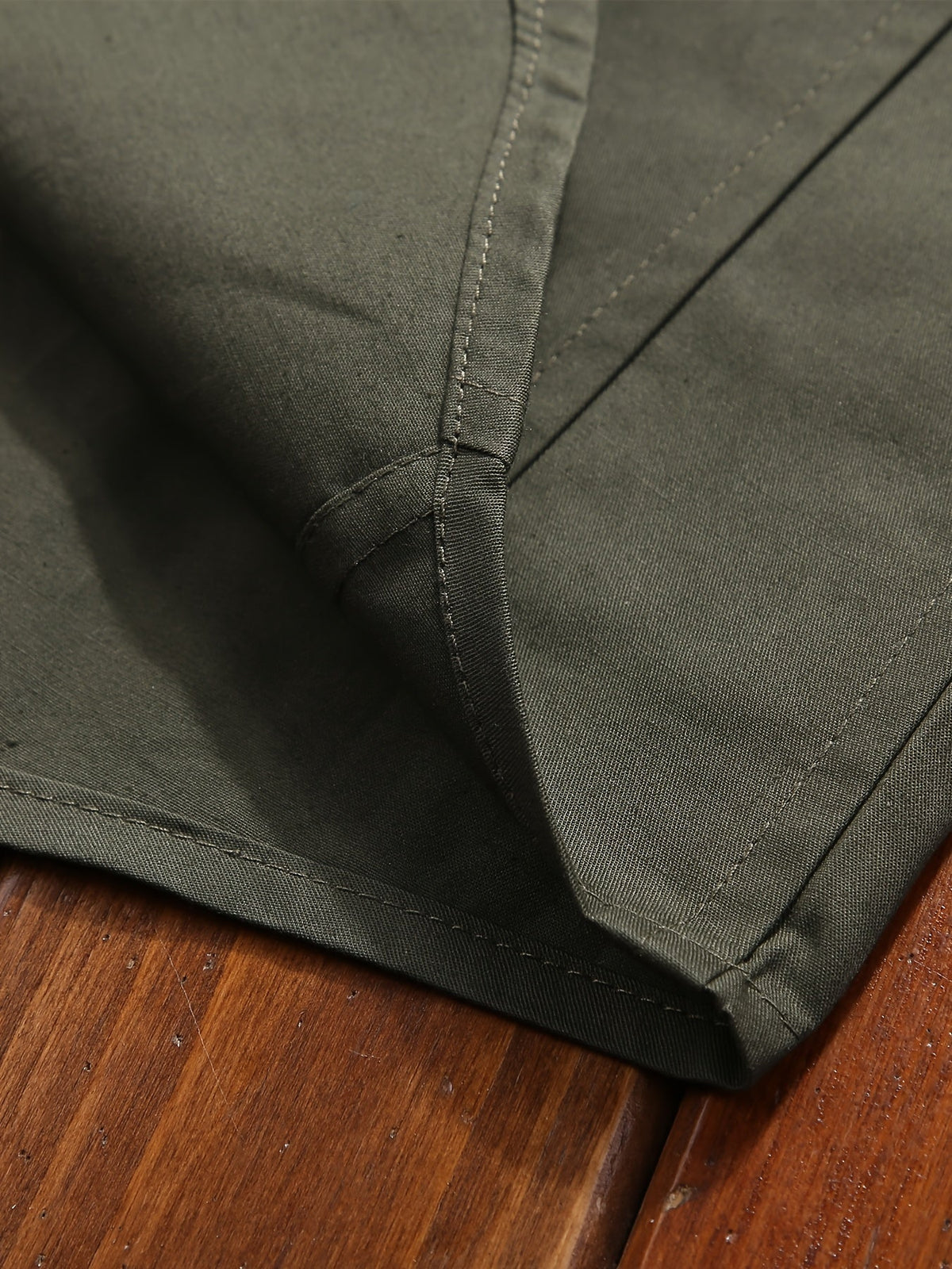Detailed view of Atmora olive green woven shirt fabric texture, clean seams and stitched hem